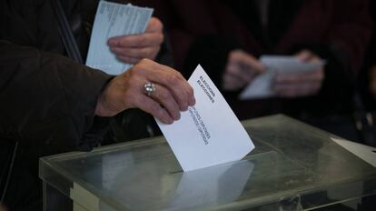 Una electora introduce su sobre de votaci&oacute;n en una urna de un colegio en Barcelona.