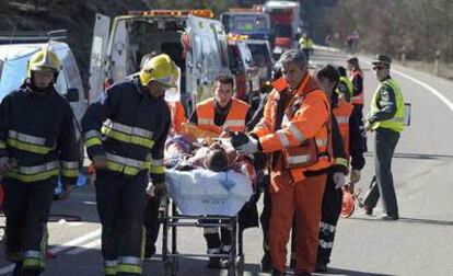 Bomberos y personal sanitario traslada hacia un helicóptero al herido grave en el accidente que se produjo al colisionar un camión y un turismo en el kilómetro 619,500 de la carretera N-330 (Alicante-Francia).