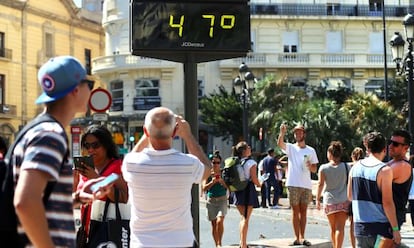 Viandantes fotografían un termómetro en el centro de Valencia, este martes.
