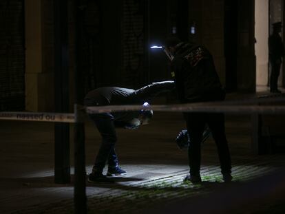 Agentes de investigacion criminal de los Mossos inspeccionan la escena del tiroteo.