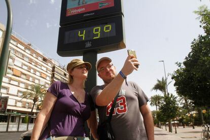 Turistas se hacen una foto junto a un termómetro de Córdoba que marca 49ºC debido a la ola de calor que en los próximos días dejarán temperaturas extremas en la Península y Baleares.