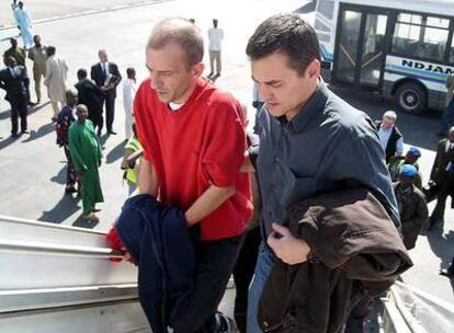 El responsable del Arca de Zoé, Eric Breteau (izquierda), sube al avión en Chad acompañado de un funcionario francés.