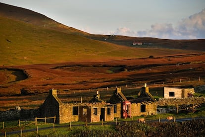 El sol brilla en un viejo edificio junto a una cabina de teléfono, en la isla de Foula.