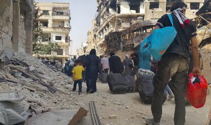 Ciudadanos sirios llevan sus pertenencias hacia los autobuses que realizarán la evacuación de Daraya.