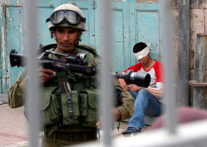 Un soldado israelí vigila a un palestino detenido durante unos enfrentamientos en la ciudad cisjordana de Hebrón, en el 'Día de la ira', convocado por Hamás por la reapertura de una sinagoga.