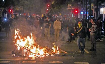 Manifestantes junto a un contenedor quemando, el jueves por la noche en Sants.