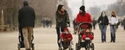 Dos madres pasean a sus hijos en un parque.