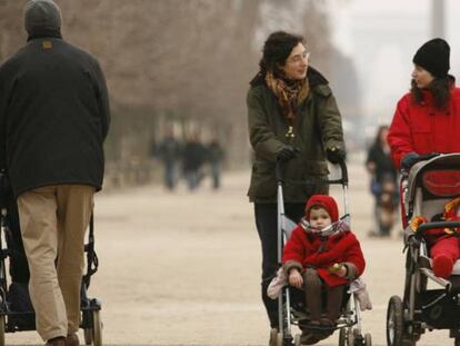 Dos madres pasean a sus hijos en un parque.