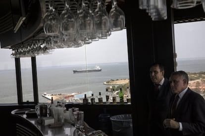 Dois garçons esperam atrás do balcão de bebidas no bar El Girasol, com vista para o Lago Maracaibo, onde um navio petroleiro está navegando. Atualmente, os dados da Comissão de Energia e Petróleo da Assembleia Nacional colocam a produção de petróleo bruto no oeste venezuelano em aproximadamente 220 mil barris por dia, uma queda de 75% em relação ao boom do petróleo que caracterizou o mandato de Hugo Chávez.