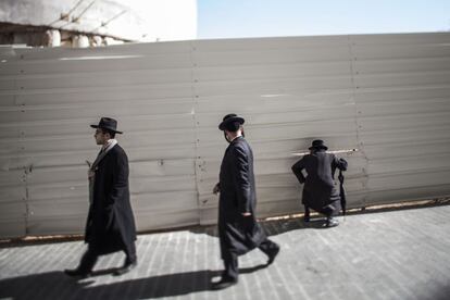 Judíos ultra ortodoxos observan a través del vallado la construcción de viviendas en el centro de Jerusalén. Cientos de ultra-ortodoxos se han congregado en protesta a los nuevos complejos de viviendas, argumentando que su edificación profanará las tumbas de los judíos que descansan en ese suelo.