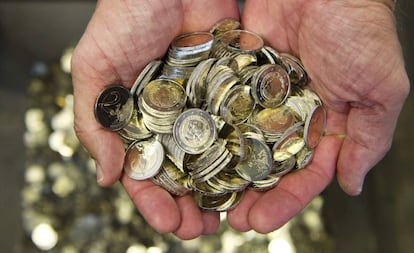 Un hombre sostiene varias monedas de euro. 