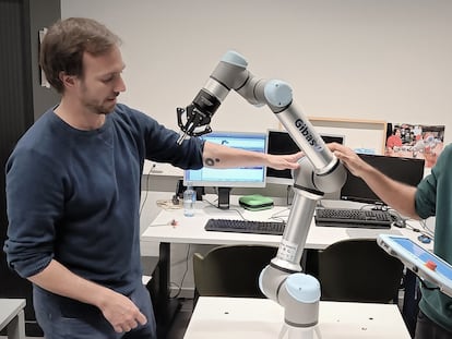 Pablo Lanillos, scientific coordinator of METATOOL (left) and postdoctoral researcher Ajith Anil Meera with one of their industrial robots.