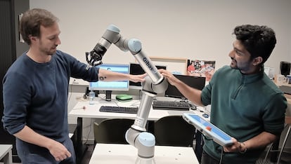 Pablo Lanillos, scientific coordinator of METATOOL (left) and postdoctoral researcher Ajith Anil Meera with one of their industrial robots.