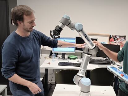 Pablo Lanillos, scientific coordinator of METATOOL (left) and postdoctoral researcher Ajith Anil Meera with one of their industrial robots.