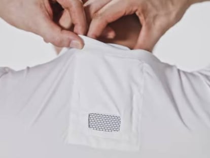 Un hombre coloca el aire acondicionado portátil en el bolsillo habilitado en la camiseta.