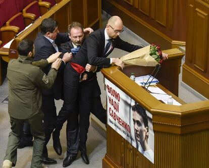 Un diputado intenta alejar al primer ministro ucraniano, Arseniy Yatsenyuk (dcha), del estrado durante la sesión parlamentaria en Kiev (Ucrania).