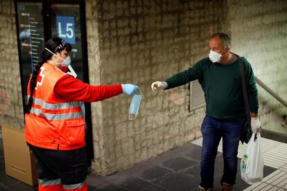 Voluntarios de Protección Civil y de Cruz Roja , en el Metro de Barcelona, donde reparten desde primera hora de la mañana en los transportes públicos de las principales ciudades catalanas mascarillas a los usuarios para tratar de evitar nuevos contagios de coronavirus, al reanudarse en parte desde este martes, trigésimo primer día de confinanamiento por el estado de alerta declarado por el Gobierno por la pandemia de coronavirus, la actividad económica.