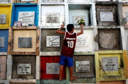 Un niño coloca un ramo de flores en una tumba, en Manila (Filipinas).