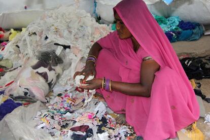 Una mujer hindú separa minuciosamente los trozos de tela de los que también saldrá material reciclado.
