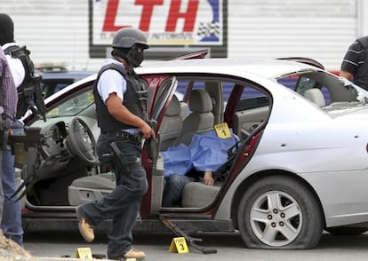 Un polic&iacute;a camina junto a un coche donde yace una v&iacute;ctima de un tiroteo en Saltillo, Coahuila (norte de M&eacute;xico).