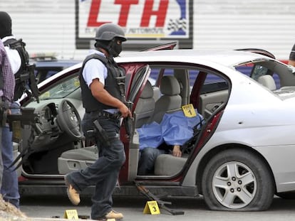 Un policía camina junto a un coche donde yace una víctima de un tiroteo en Saltillo, Coahuila (norte de México).