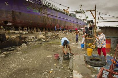 Varias personas recogen agua en Tacloban, una de las zonas más afectadas por el tifón Haiyan de 2013, en octubre de 2014.