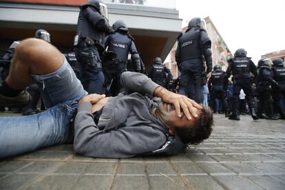 Un hombre cae al suelo durante la carga de los antidisturbios (UIP) de la Policía Nacional en la Escola Mediterránea de la Barceloneta en Barcelona. Incidentes entre votantes y Guardia Civil y Policía Nacional en el día del referéndum ilegal independentista catalán del 1-O. Desafío independentista en Cataluña.