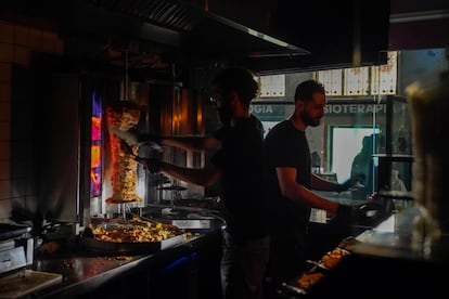Dos trabajadores de un Kebab preparan pedidos a oscuras en el centro en Madrid, el 28 de abril. 