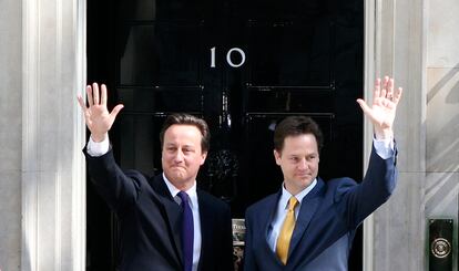 El primer ministro David Cameron, y su número dos, el viceprimer ministro Nick Clegg saludan a la prensa desde el 10 de Downing Street.