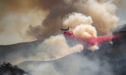 Un avión vierte fuego ignífugo en una ladera en un intento de encajonar entre llamas un incendio forestal, en Rumsey, California (EE UU).