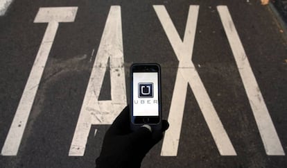 Un móvil con el logo de Uber sobre una parada de taxi