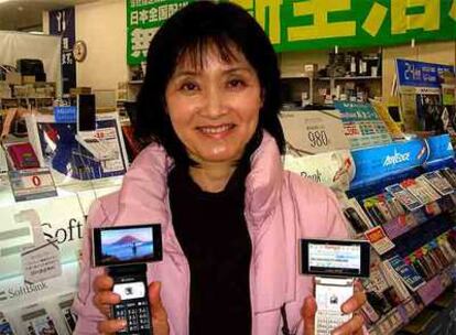 Una japonesa muestra la televisión en su móvil, en una tienda de Tokio.