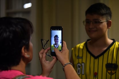Una mujer saca una fotografía a su hijo portando su nuevo par de anteojos.