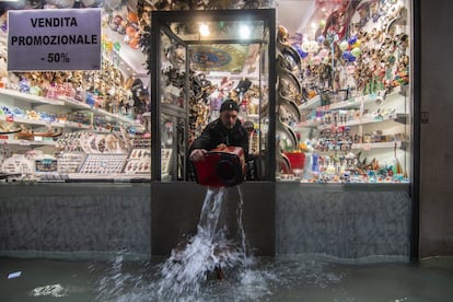Un comerciante saca agua de su tienda durante una marea alta excepcional, en Venecia.