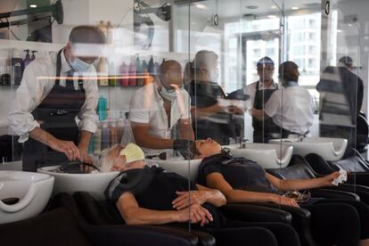 Varios empleados de una peluquería atienden a las clientas entre mamparas para evitar el contagio por coronavirus en Bella Rinova en Houston (EE UU).