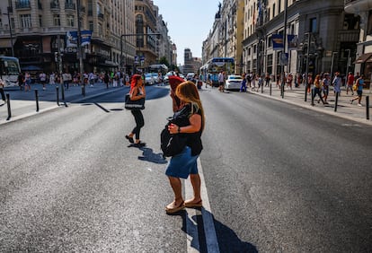 Una mujer camina este lunes por la Gran Vía de Madrid, refrescándose con un abanico.