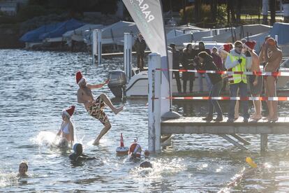Varios participantes del tradicional baño de Navidad saltan al agua del lago Lugano, a 8 grados de temperatura, este jueves, en Paradiso (Suiza), con motivo del día de San Esteban. Unos 80 nadadores han tomado parte en el evento acuático.