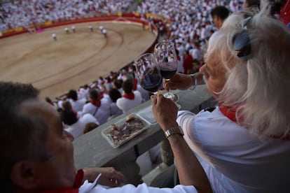 Unos espectadores difrutan de una copa de vino durante una corrida en la plaza de toros de Pamplona, el 14 de julio de 2017.