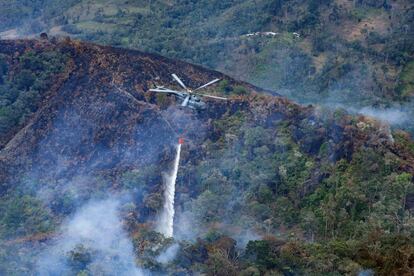 Un helicóptero con sistema Bambi bucket se desplaza entre uno de los incendios en la Florida, Perú, este 17 de septiembre.