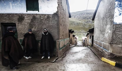 Tres hombres se protegen del frío en los Andes peruanos.