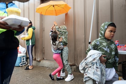 Dos niños juegan mientras su madre lleva contenedores de comida fuera de un refugio para inmigrantes en South Halsted Street (Chicago), en abril de 2024.