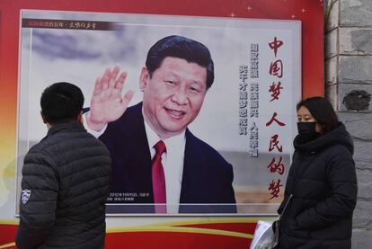 Duas pessoas passam diante de um cartaz com a foto do presidente Xi Jinping em Pequim, nesta segunda-feira.