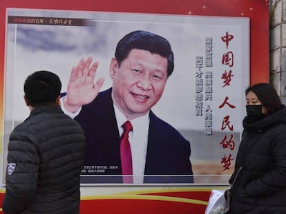 Duas pessoas passam diante de um cartaz com a foto do presidente Xi Jinping em Pequim, nesta segunda-feira.