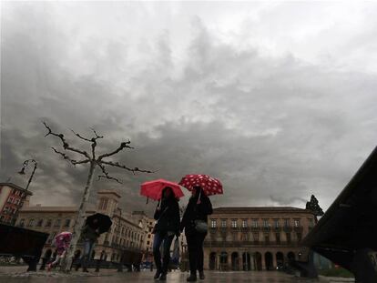 Dos personas se protegen del agua con un paraguas este sábado en la plaza del Castillo de Pamplona.