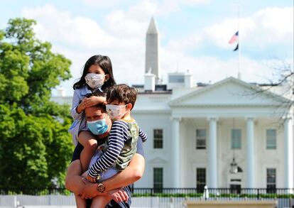 Una familia posa ante la Casa Blanca, donde lucen las banderas a media asta en recuerdo a las víctimas del coronavirus.