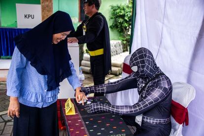 Trabajadores electorales indonesios vestidos con trajes de superhéroes registran a los votantes en una mesa electoral en Surabaya.