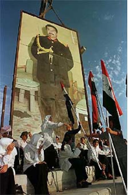 Estudiantes iraquíes celebran el Día de Bagdad ante un enorme cartel de Sadam Husein.