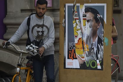 Un ciclista pasa por delante de un cartel electoral desgarrado del líder de Ciudadanos Albert Rivera, en una calle de Barcelona.