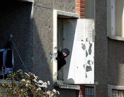 Un policía mira por la ventana del edificio asaltado.