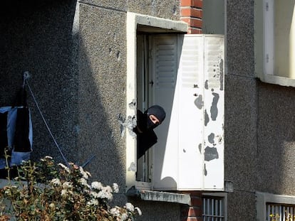 Un policía mira por la ventana del edificio asaltado.